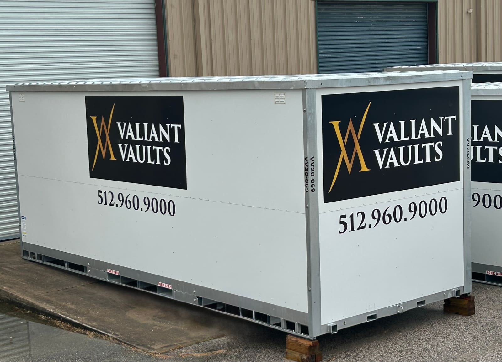 Side view of a steel Valiant Vaults portable storage container with gold and black branding